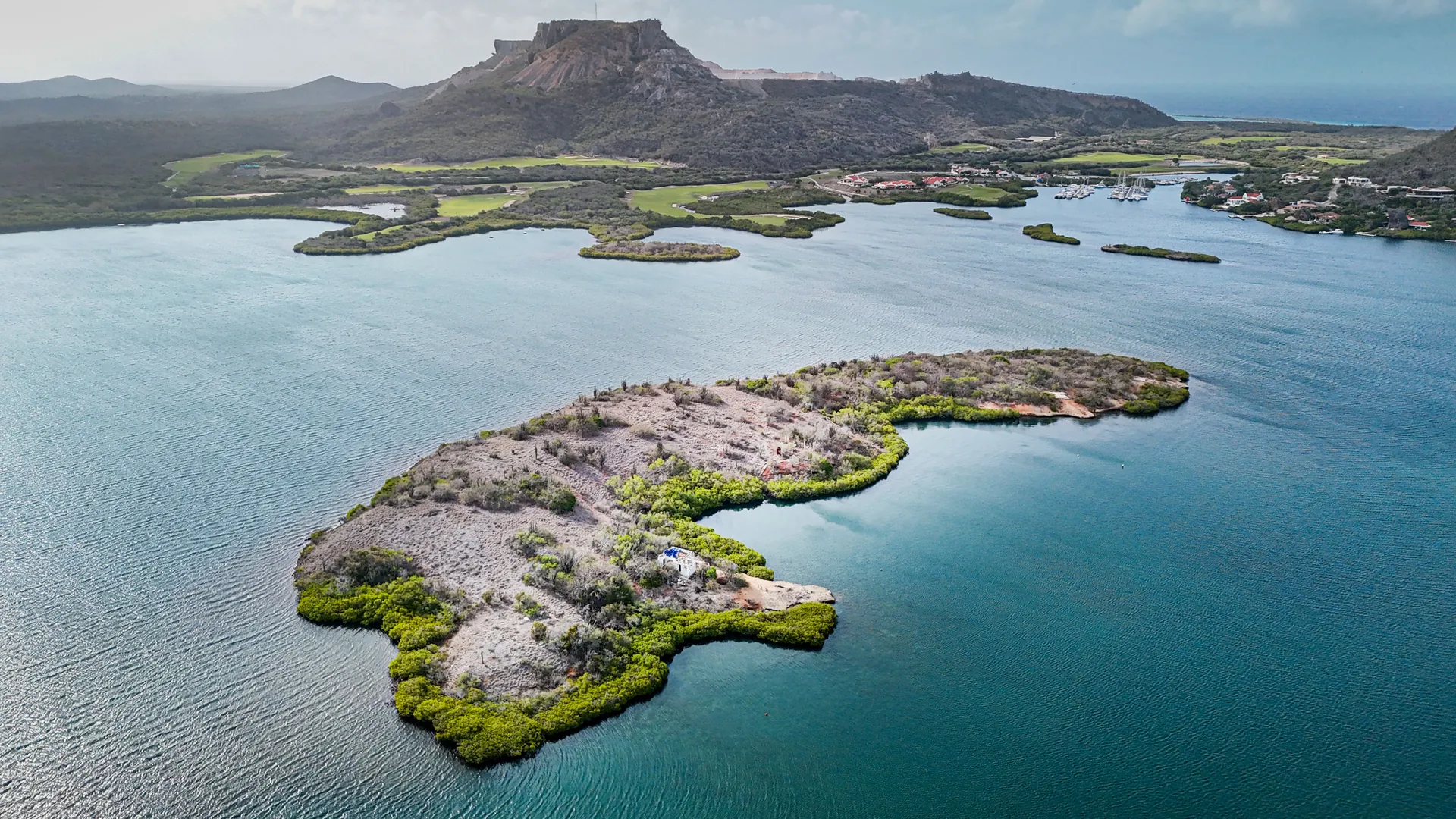 Aerial photograph of Isla di Yerba across Spanish Water with the Tafelberg ridge rising behind the mainland shore.